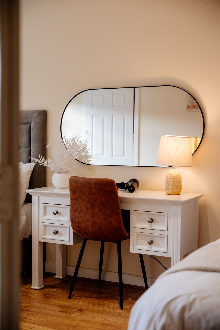 White desk with an oval mirror, lamp and hairdryer in a bedroom in Abbeyhill
