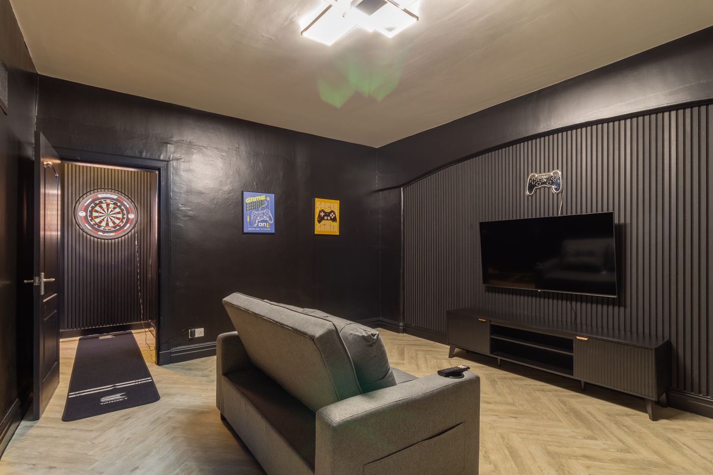 Games room with a TV, sofa and dartboard, in a home we look after in Dalkeith