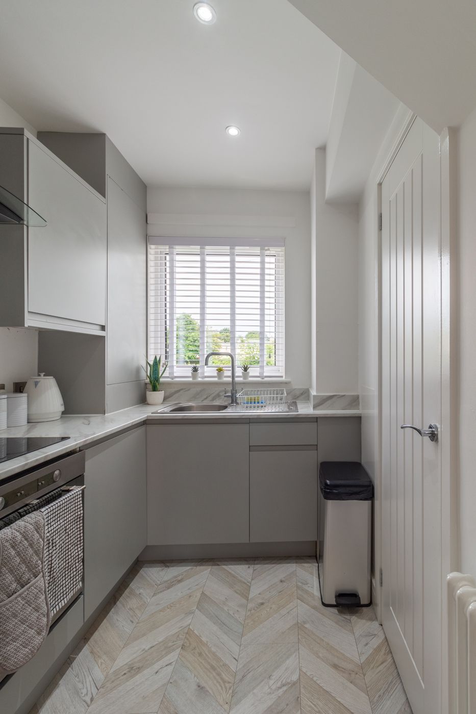 Grey fitted kitchen with a marble-effect worktop and garden view, in Prestonfield
